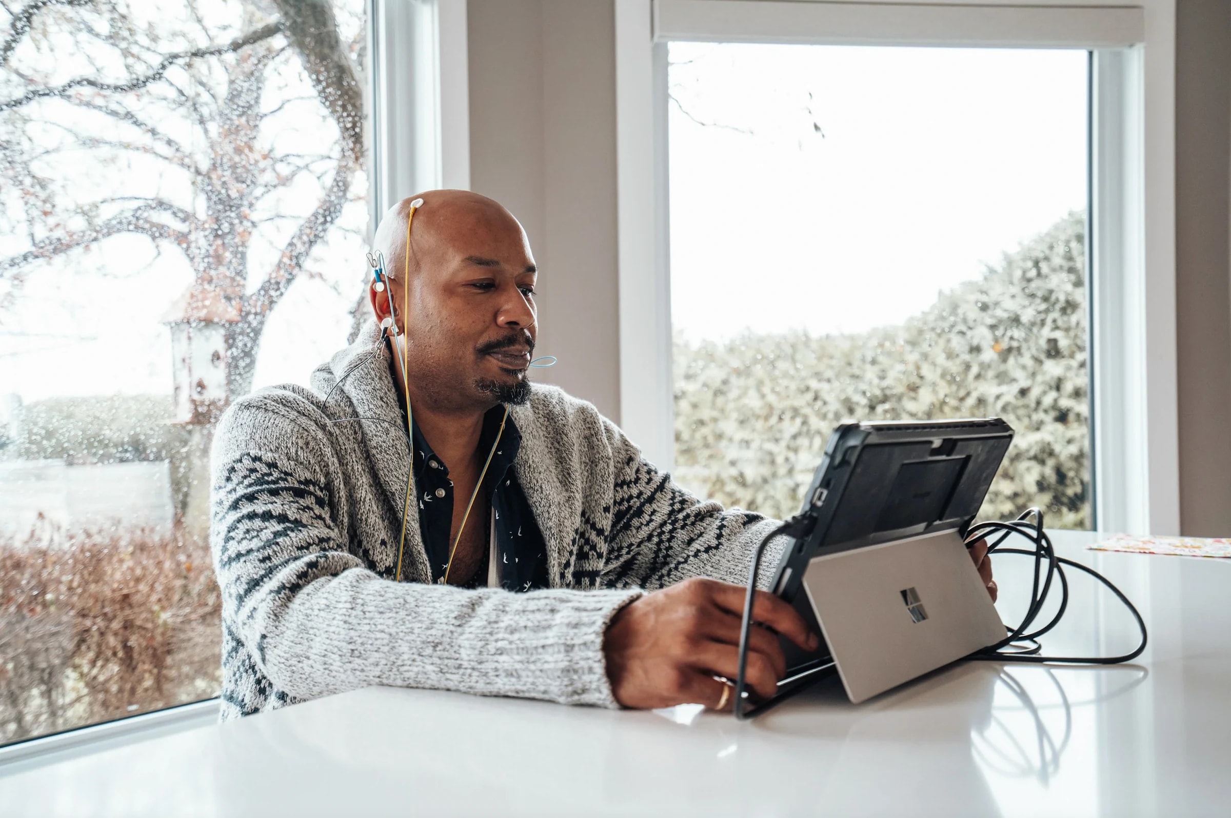 A man doing a neurofeedback session at home with sensors and a tablet