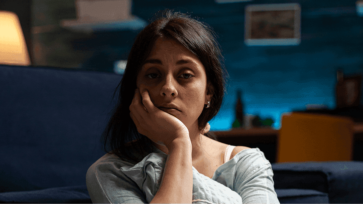 Tired woman sitting up late at night, resting her head on her hand