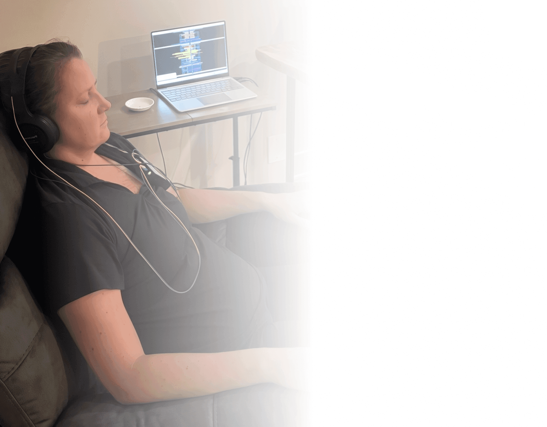 Client relaxing in a recliner with a neurofeedback headset beside a laptop